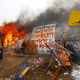Protest signs near a burning structure at an opposition camp. (Reuters/Terray Sylvester)